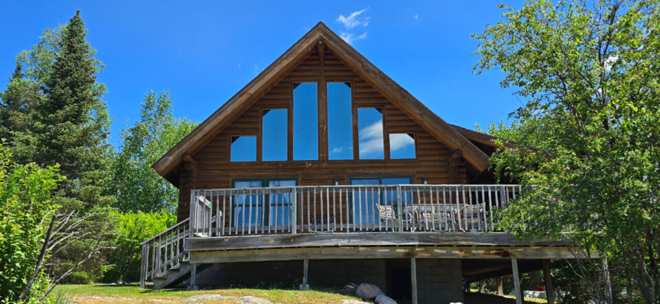 Rustic log cabin with large windows and wooden deck