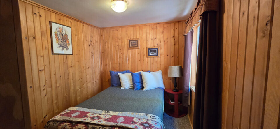 Cozy cabin bedroom with wood paneling and blue pillows