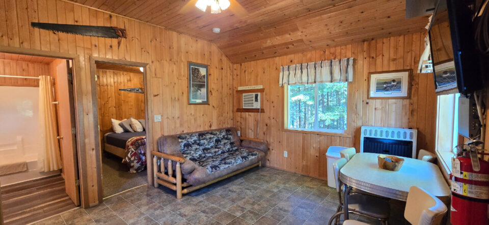 Cozy rustic wooden cabin interior with futon and dining area
