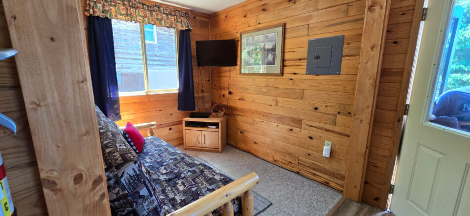 Cozy rustic cabin bedroom with log bed and wall-mounted TV
