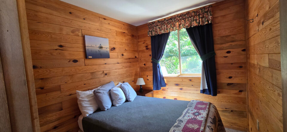 Cozy rustic cabin bedroom with wood walls and blue curtains