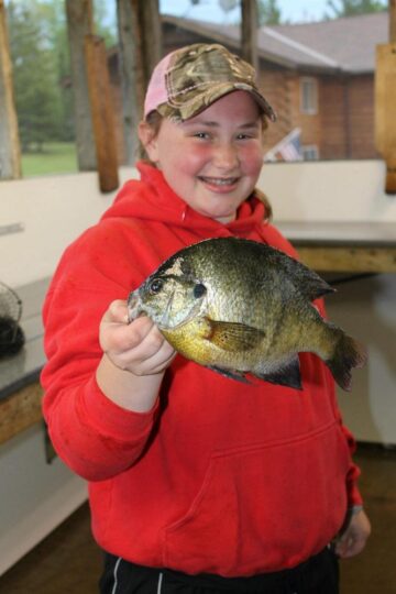Smiling girl in red hoodie holding large bluegill fish